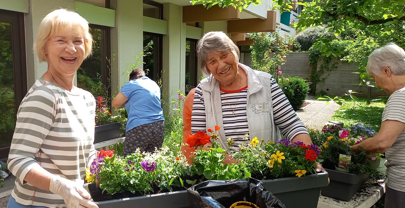 Mieterinnen bepflanzen gemeinsam die Blumenkästen